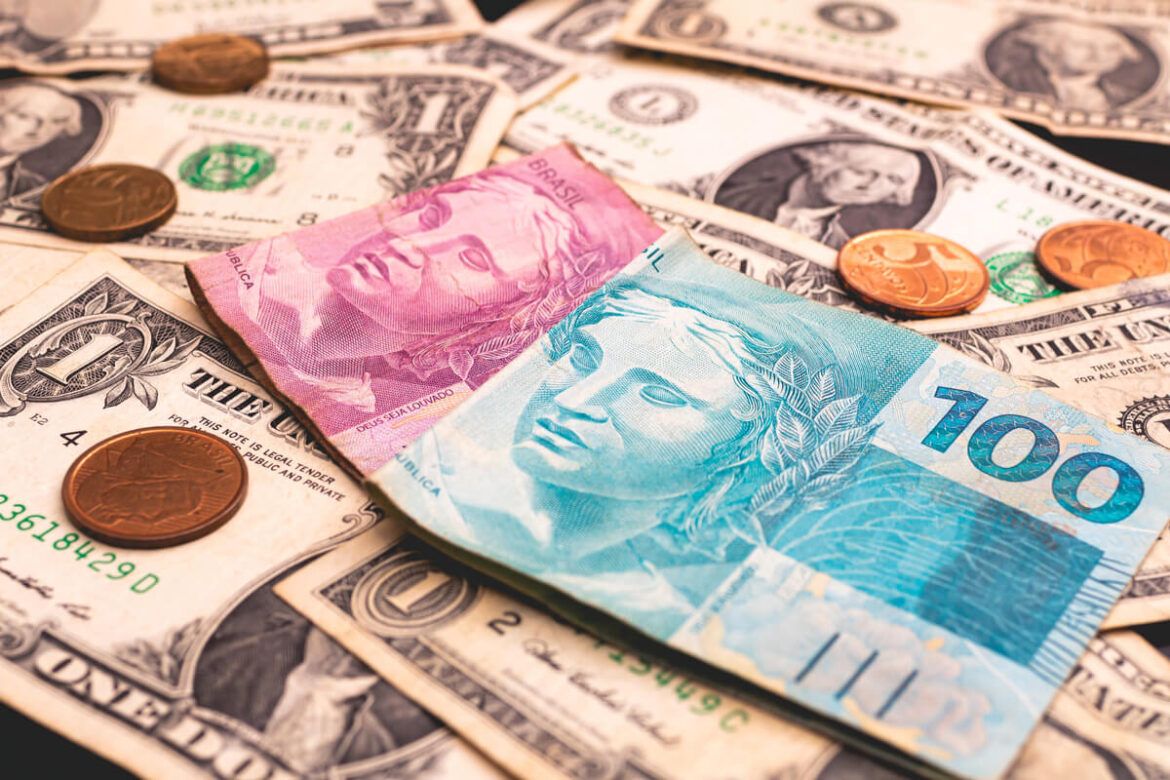 notas de dólar e real em cima de uma mesa