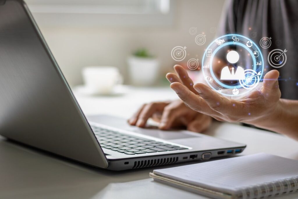 Pessoa digitando no notebook com um ícone de persona sobre a mão.