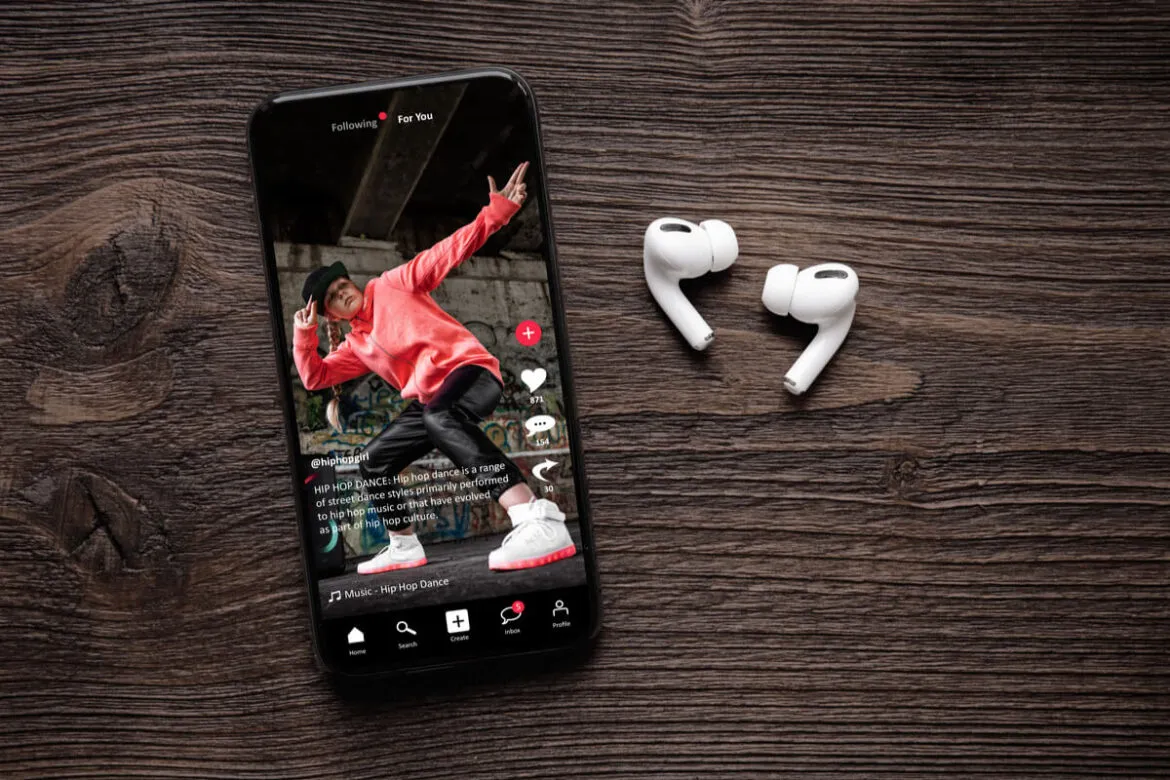 Um smartphone mostrando um vídeo do Rells e ao lado fones de ouvido sem fio