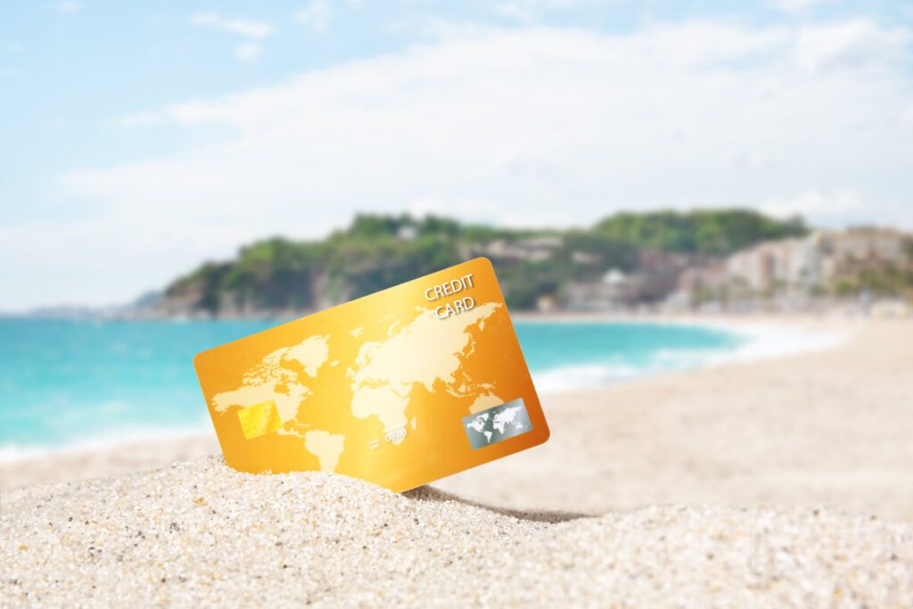 Um cartão de crédito fincado na areia de uma bela praia