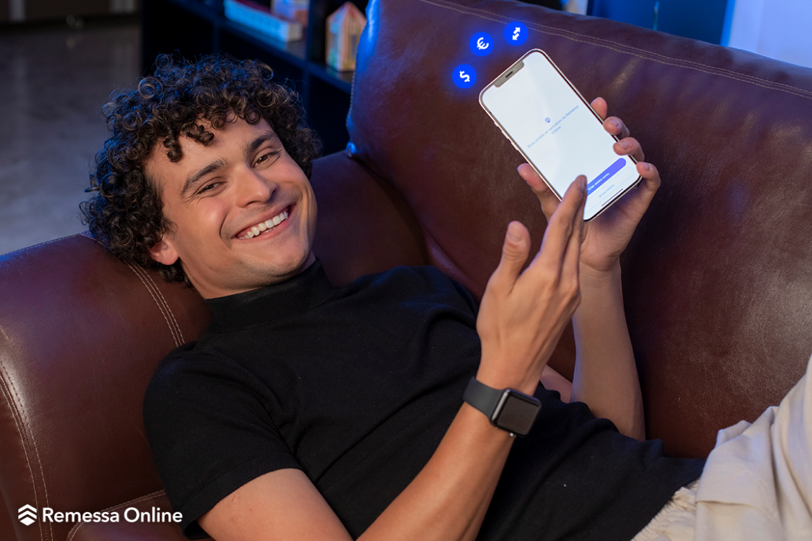 Max Petterson deitado em sofá apontando para celular com o app da Remessa Online aberto