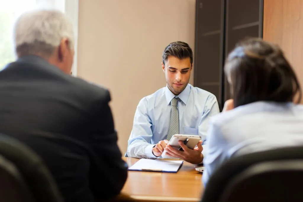 Três pessoas sentadas em uma mesa verificando o método venture capital.