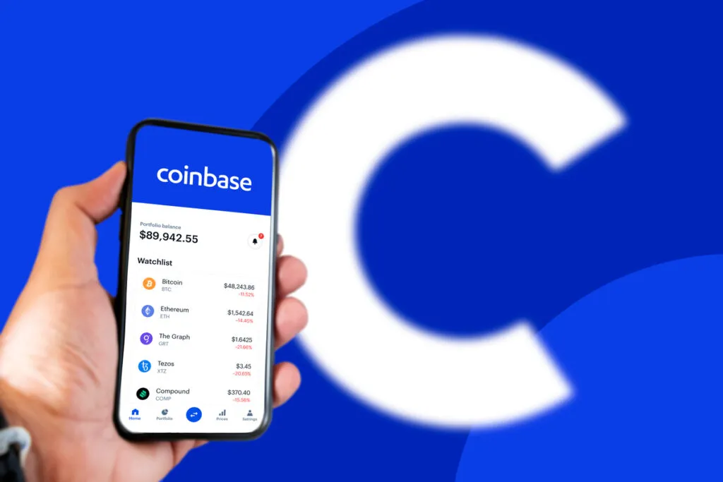 Um celular em um dashboard da coinbase e ao fundo o logotipo da empresa