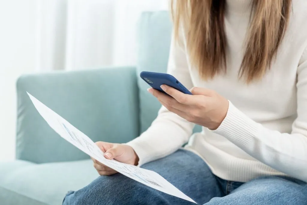 Mulher acessando o internet banking do celular para conferir o DDA do boleto. 