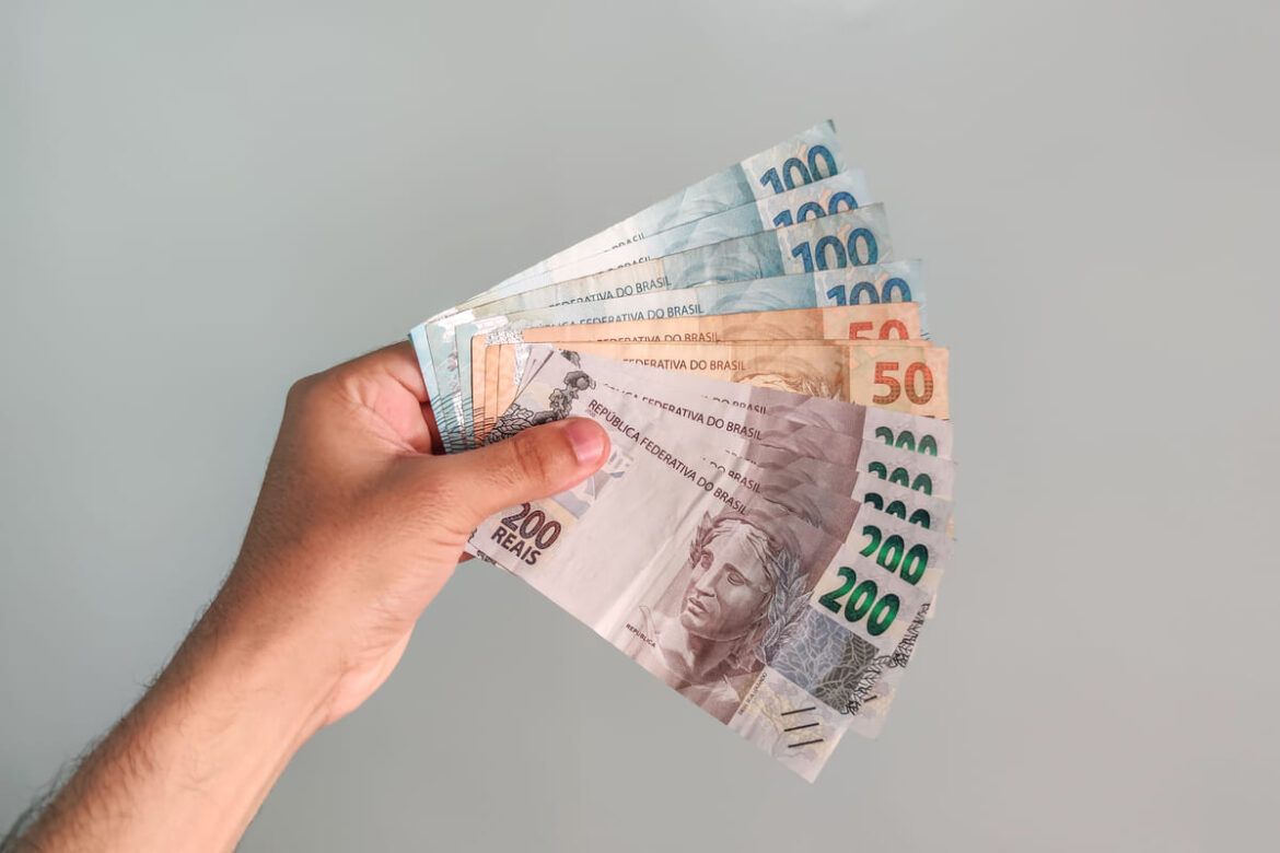 Pessoa segurando dinheiro em reais simulando empréstimo consignado Auxílio Brasil pela Caixa