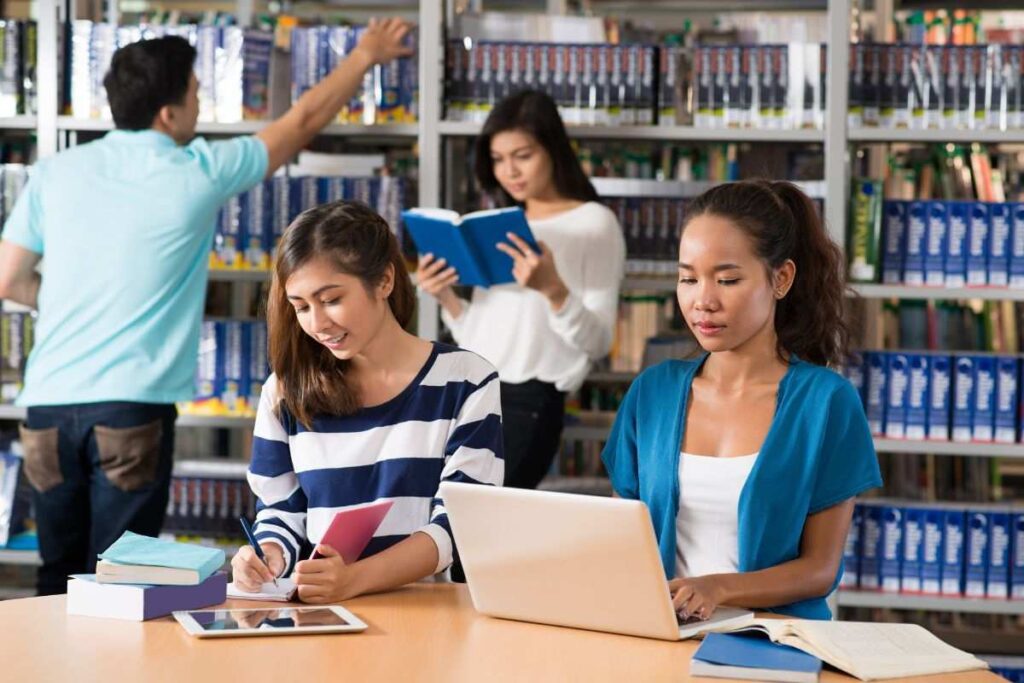 Grupo de alunos na biblioteca pesquisando por bolsas para estudar na Inglaterra.