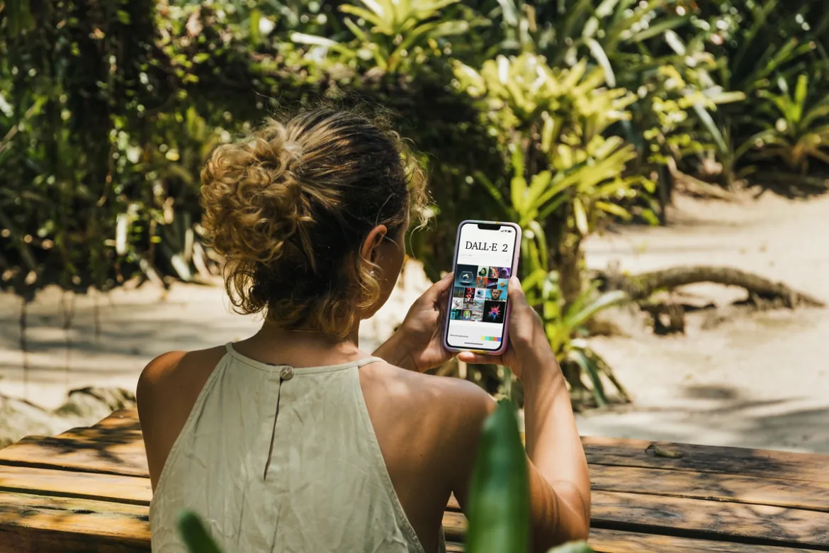 Foto de mulher de costas segurando um celular com a tela do DALL-E 2 aberta