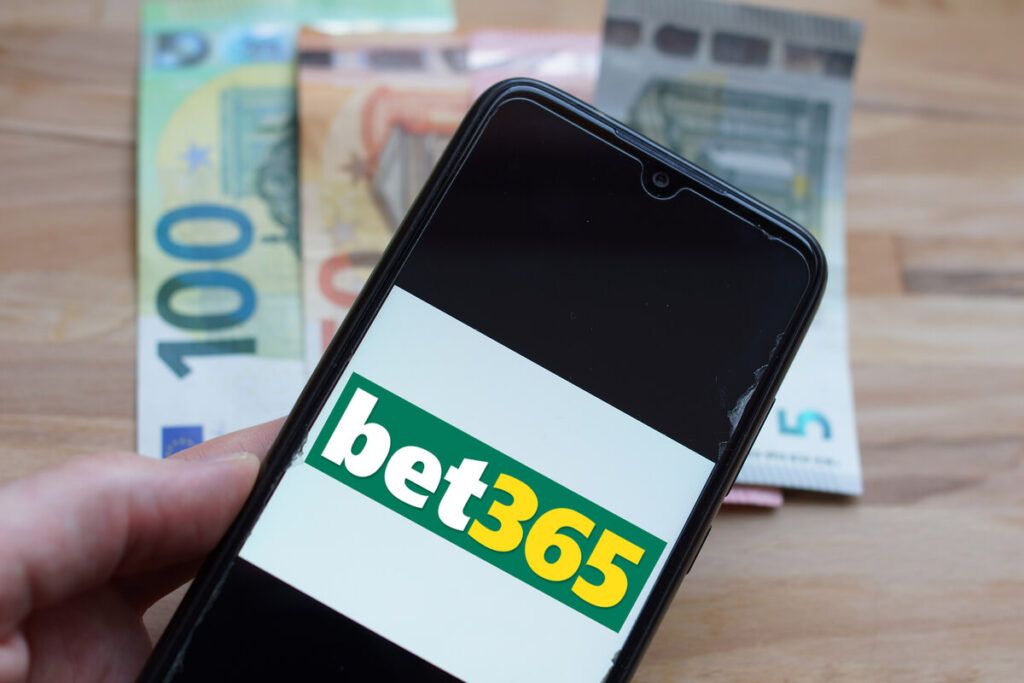 Um celular com o logotipo do Bet365 e notas de dinheiro ao fundo