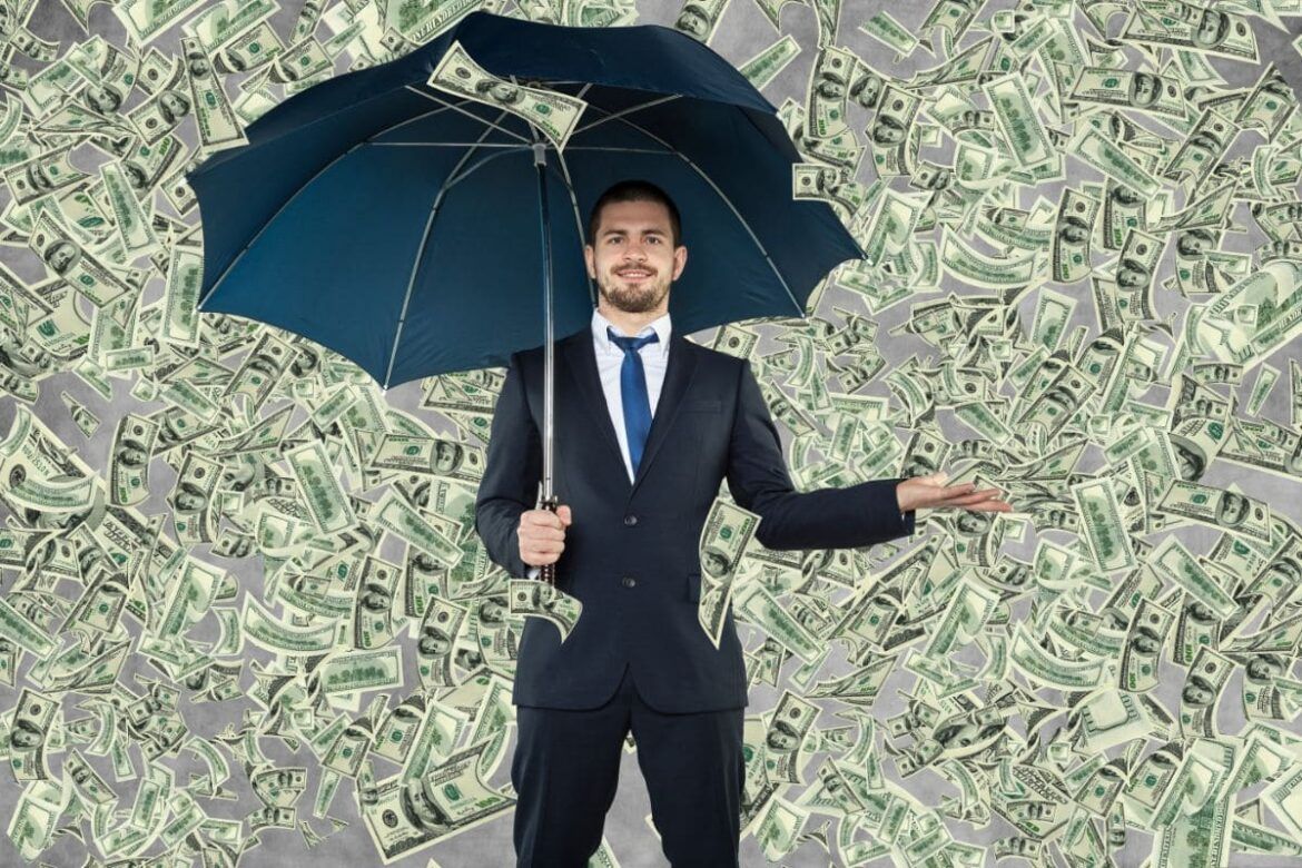 Homem segurando guarda-chuva para se proteger da chuva de dinheiro, simulando bilionários russos.