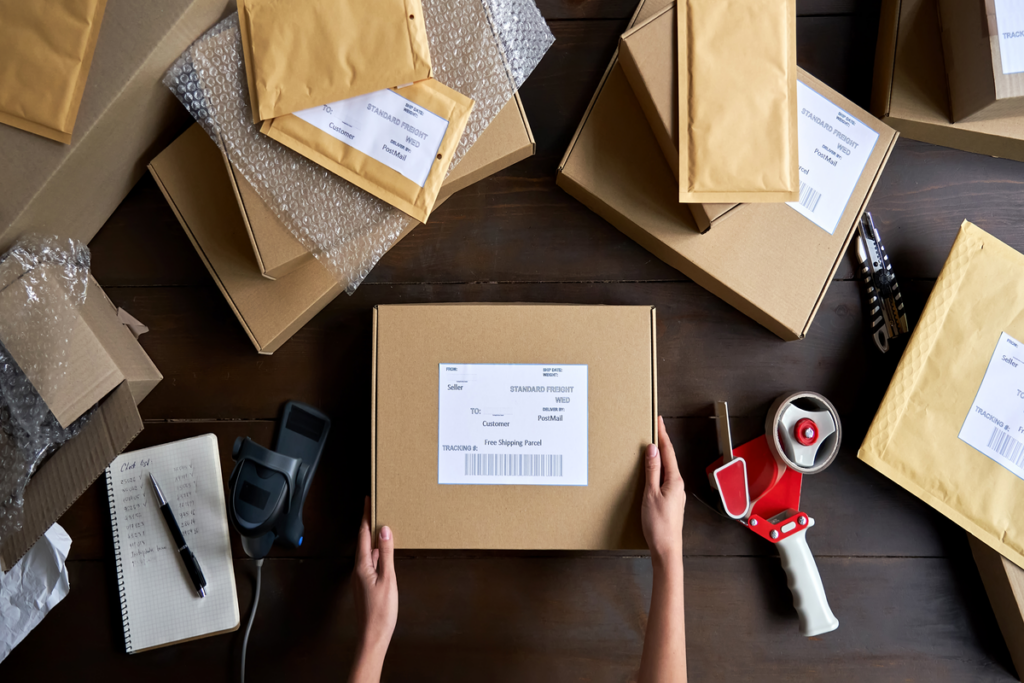 Foto de uma pessoa embrulhando uma caixa com vários pacotes em volta
