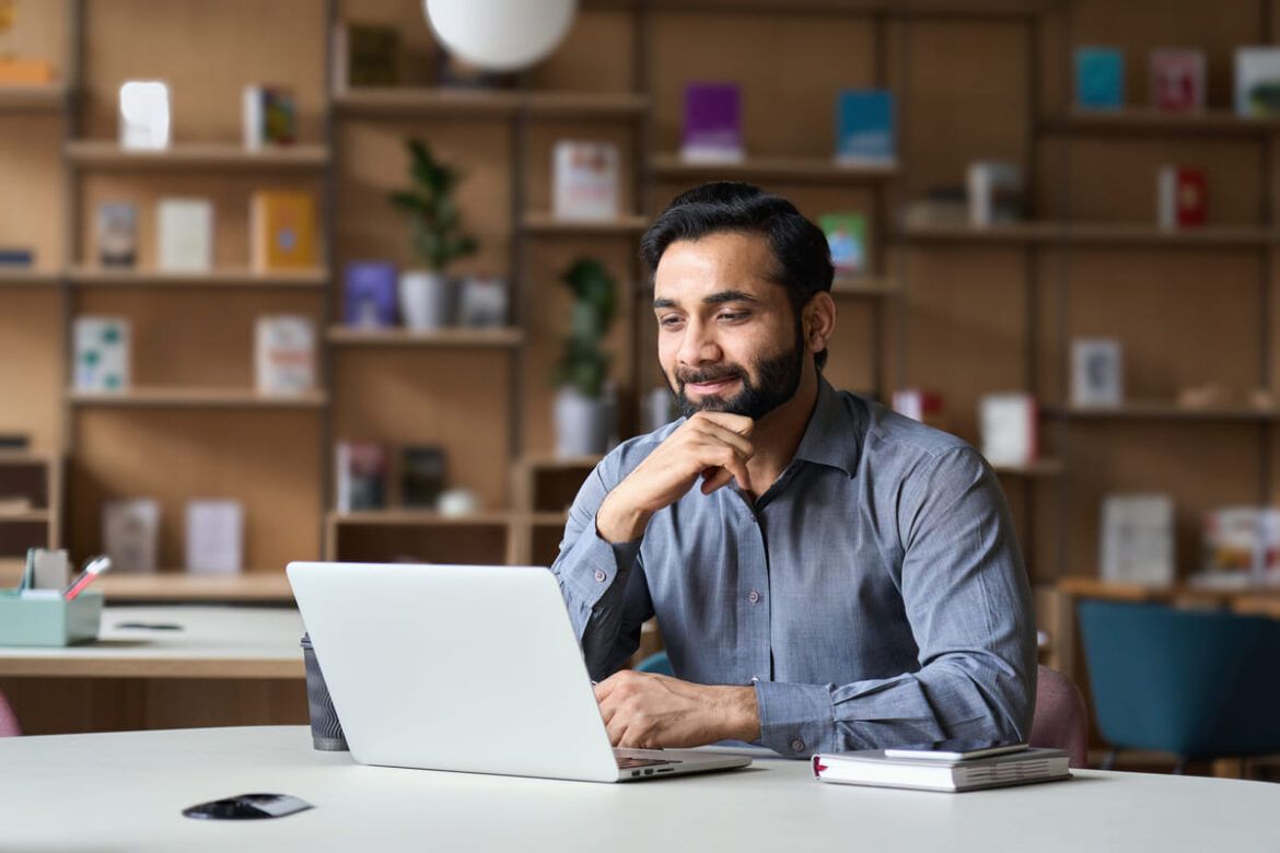 Homem mexendo no computador para conferir informações sobre o visto para procurar emprego em Portugal.