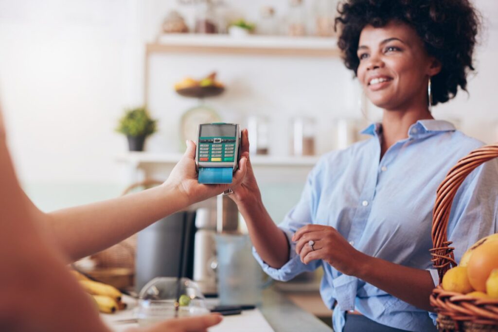 Empreendedora recebendo pagamento na maquininha da conta digital Safra.