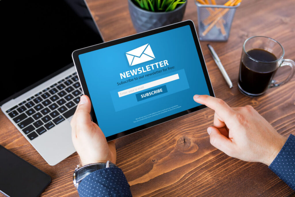 Imagem de um homem segurando um tablet, com uma newsletter.