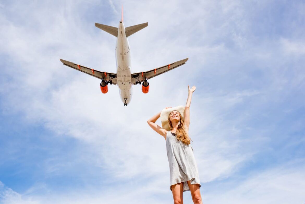 Mulher sorrindo com avião voando ao fundo para ilustrar um texto sobre 123 Milhas