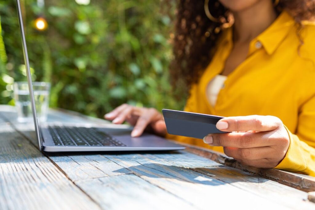 Mulher segurando o cartão e digitando no computador
