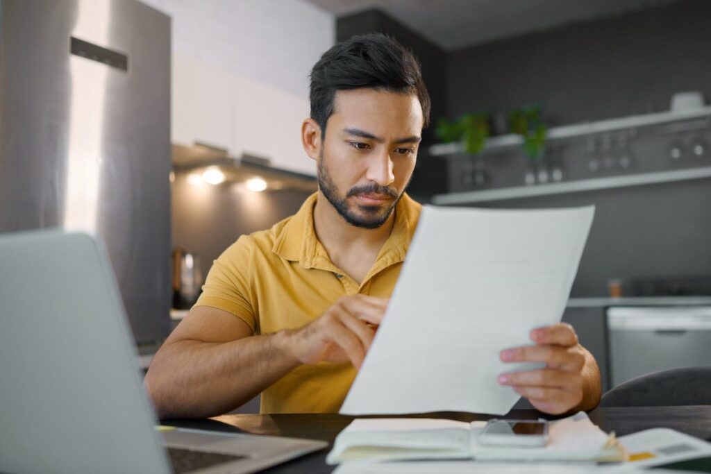 Homem lendo o relatório para declarar o dinheiro no imposto de renda recebido do YouTube.