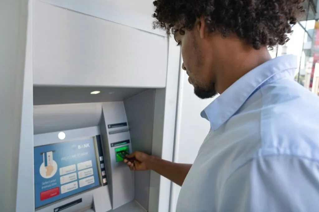 Homem sacando dinheiro do PayPal no caixa eletrônico.