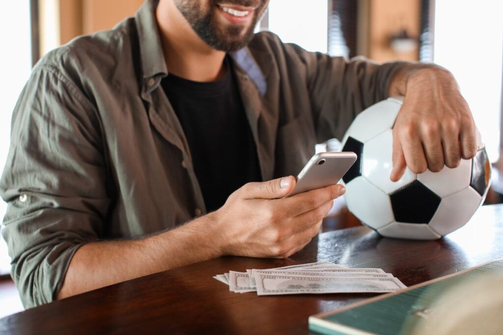 Homem com celular na mão aprendendo como sacar dinheiro do SportingBet.