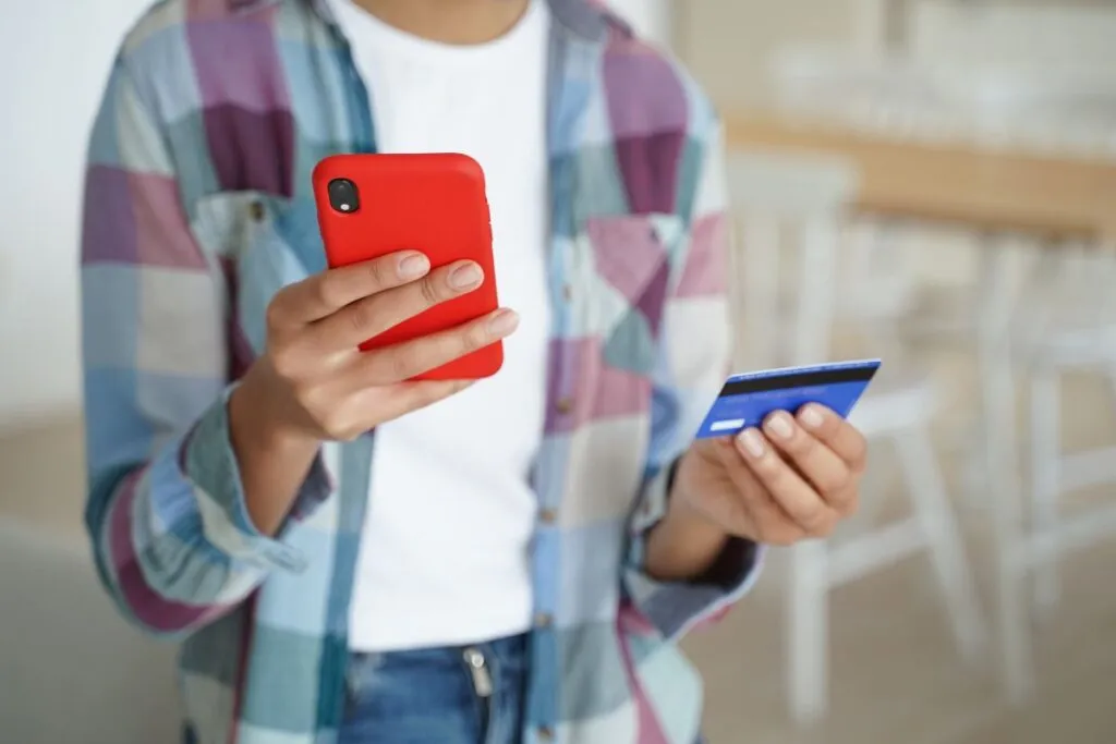 Mulher com smartphone na mão e cartão de crédito. 