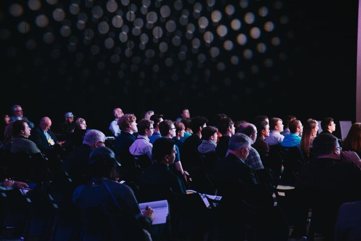Pessoas sentadas assistindo a uma palestra, simulando ser no ANBIMA Summit.