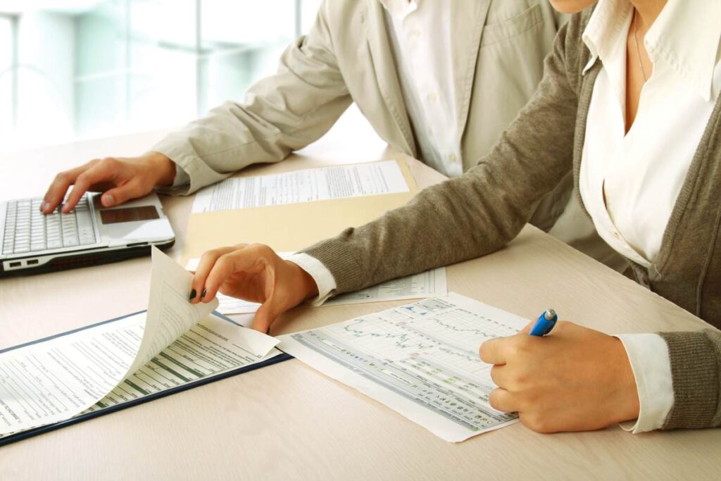 Homem e mulher preenchendo documento com código do banco BTG Pactual.