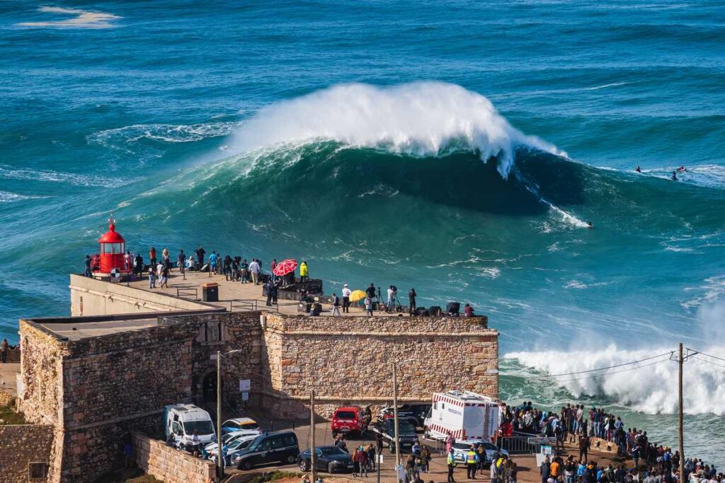 Turistas no Farol de Nazaré, Portugal admirando as ondas.