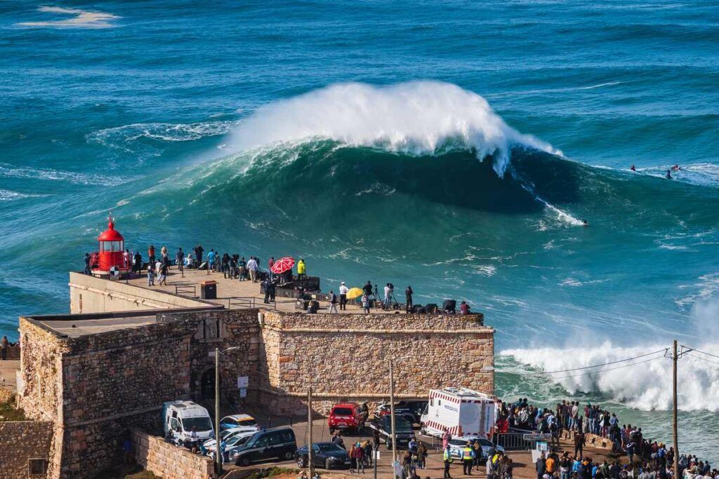 Turistas no Farol de Nazaré, Portugal admirando as ondas. 