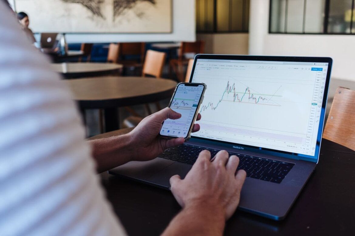 Uma pessoa mexendo no celular e no computador na plataforma NinjaTrader, que oferece trading integrado em diferentes dispositivos para acessar os mercados futuros mais populares.