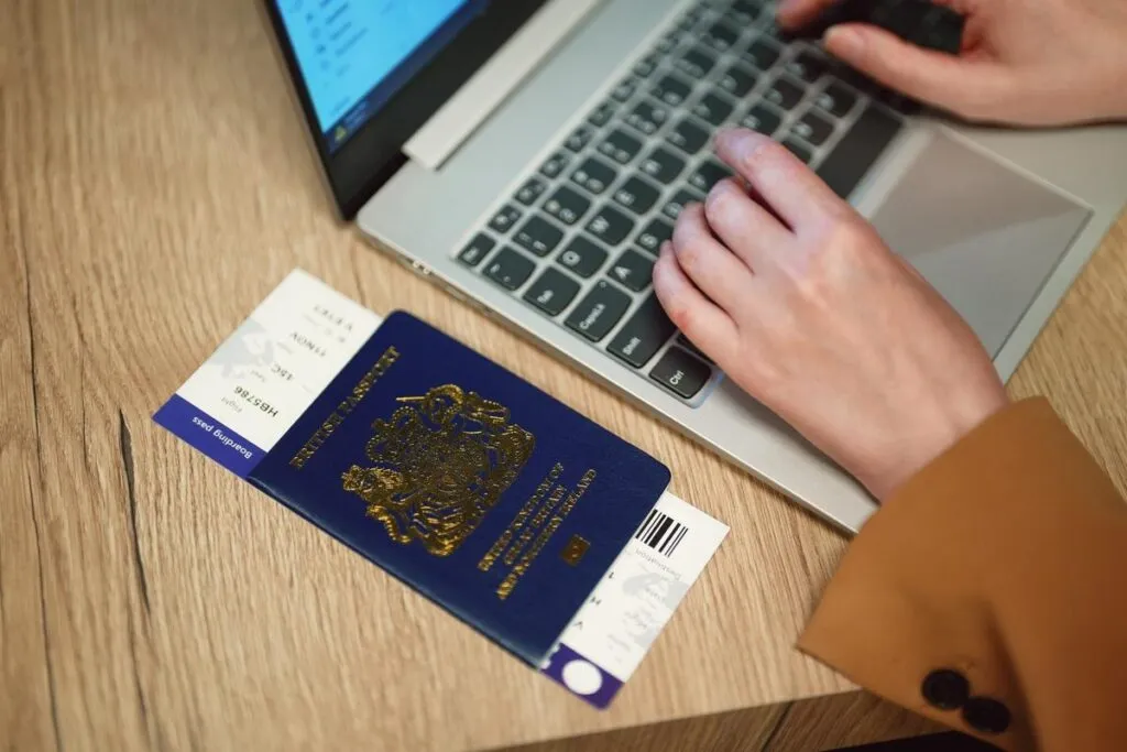 Mulher acessando a internet com passaporte ao lado do notebook. 