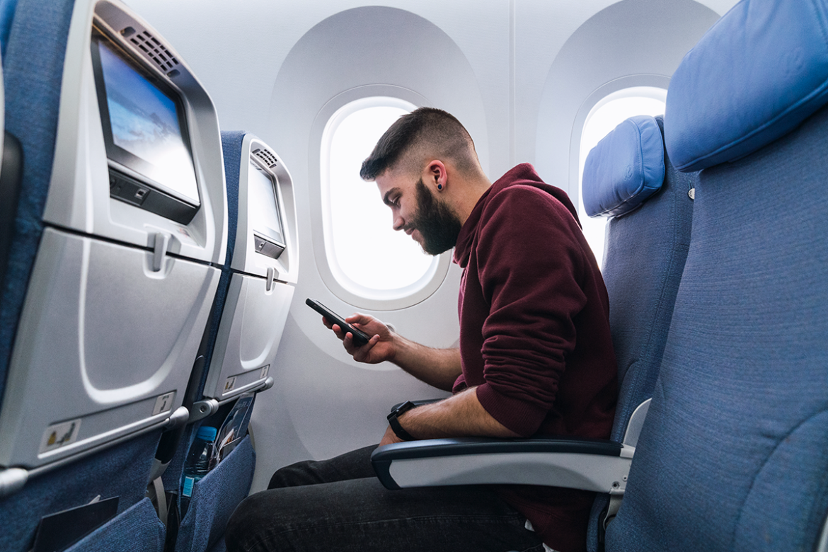 Um jovem ao celular dentro de um avião
