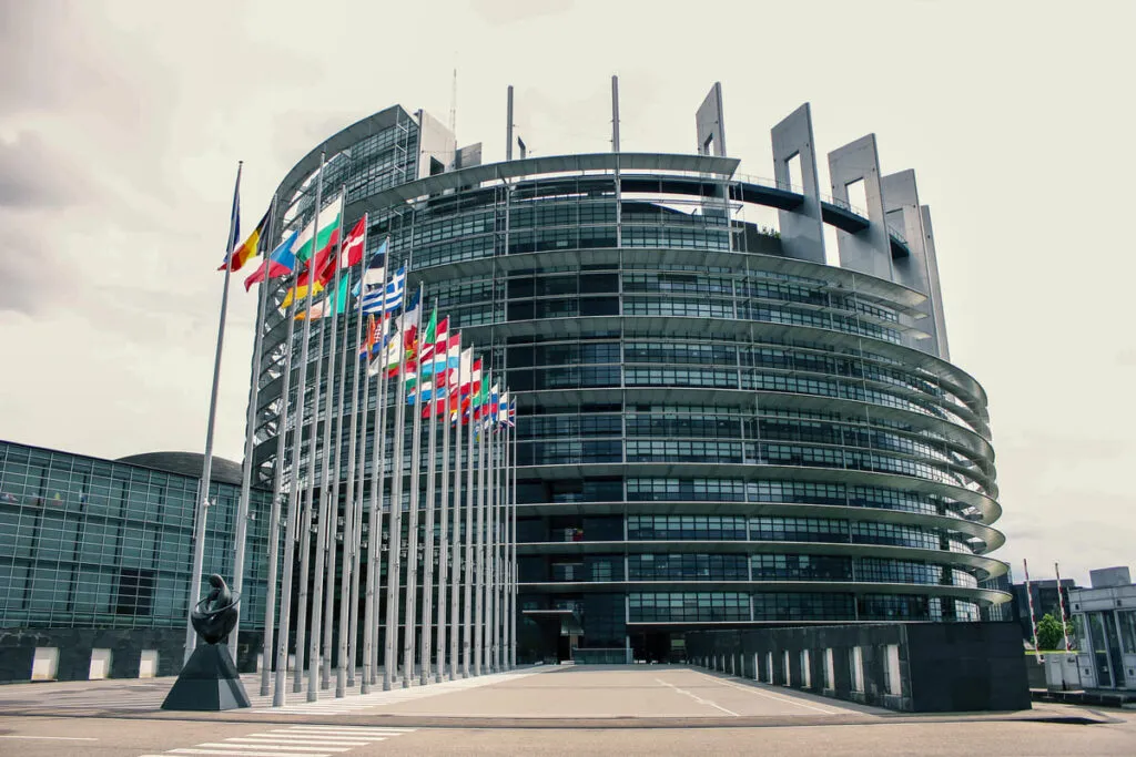 Prédio do Parlamento Europeu, com bandeiras dos países-membros da União Europeia.