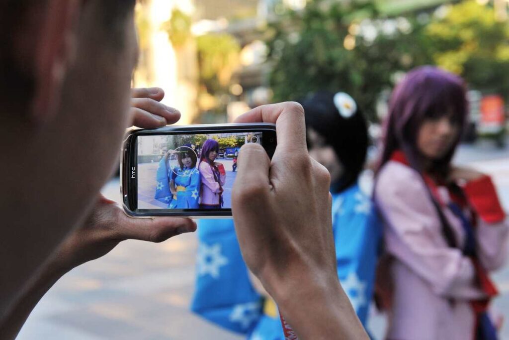 Homem tirando foto de cosplayers durante evento.