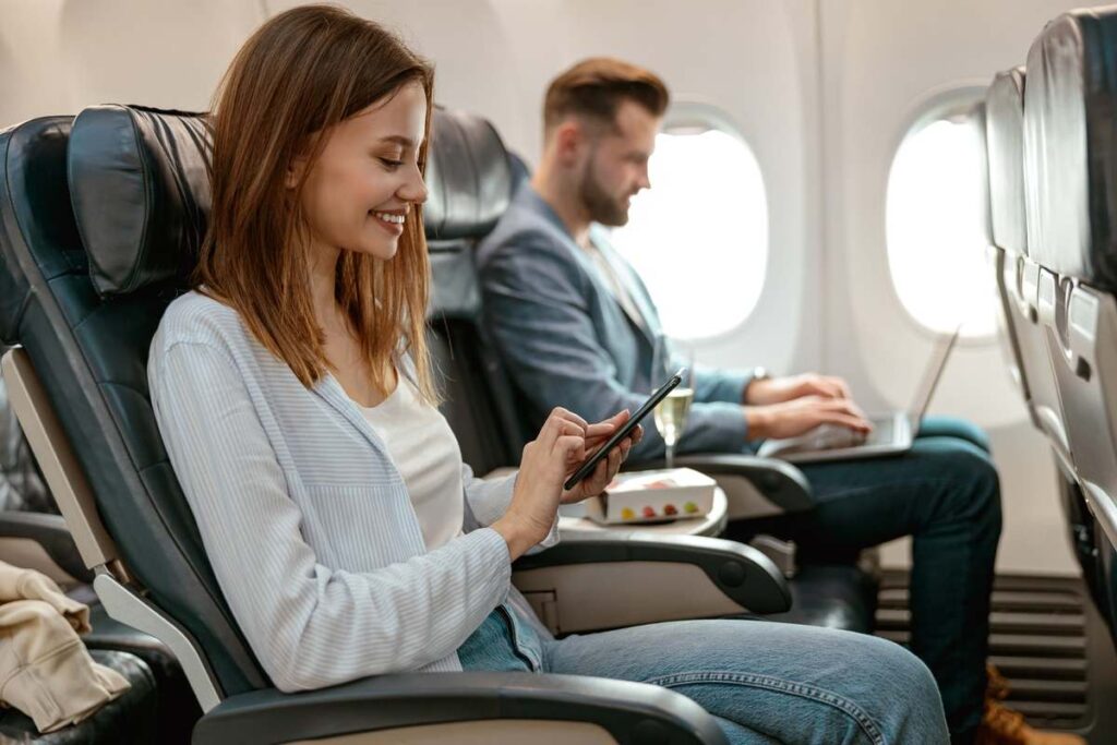 Mulher no avião acessando o grupo da Travel Tec Hub no WhatsApp.