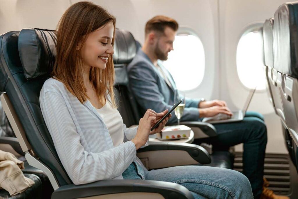 Mulher no avião acessando o grupo da Travel Tec Hub no WhatsApp. 