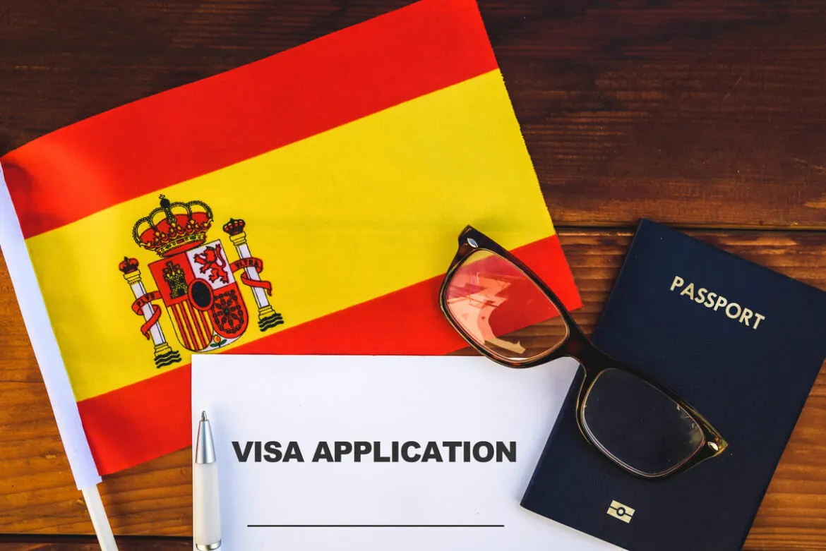 Imagem mostra visto para Espanha, bandeira do país e um passaporte.