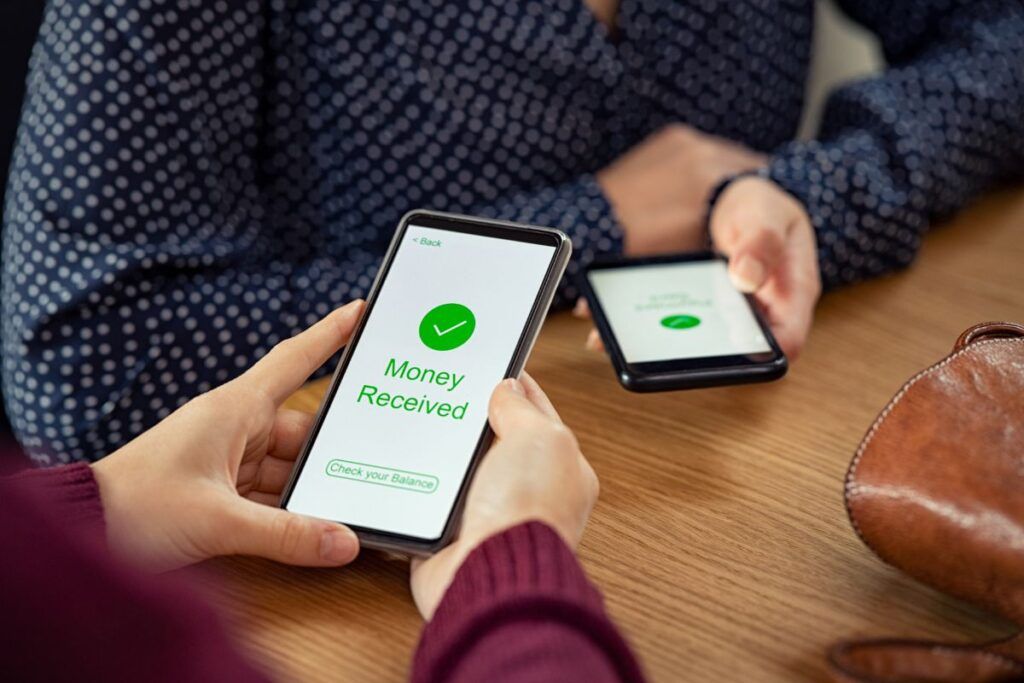 Homem e mulher olhando o celular com transferência de dinheiro do Wishtender.