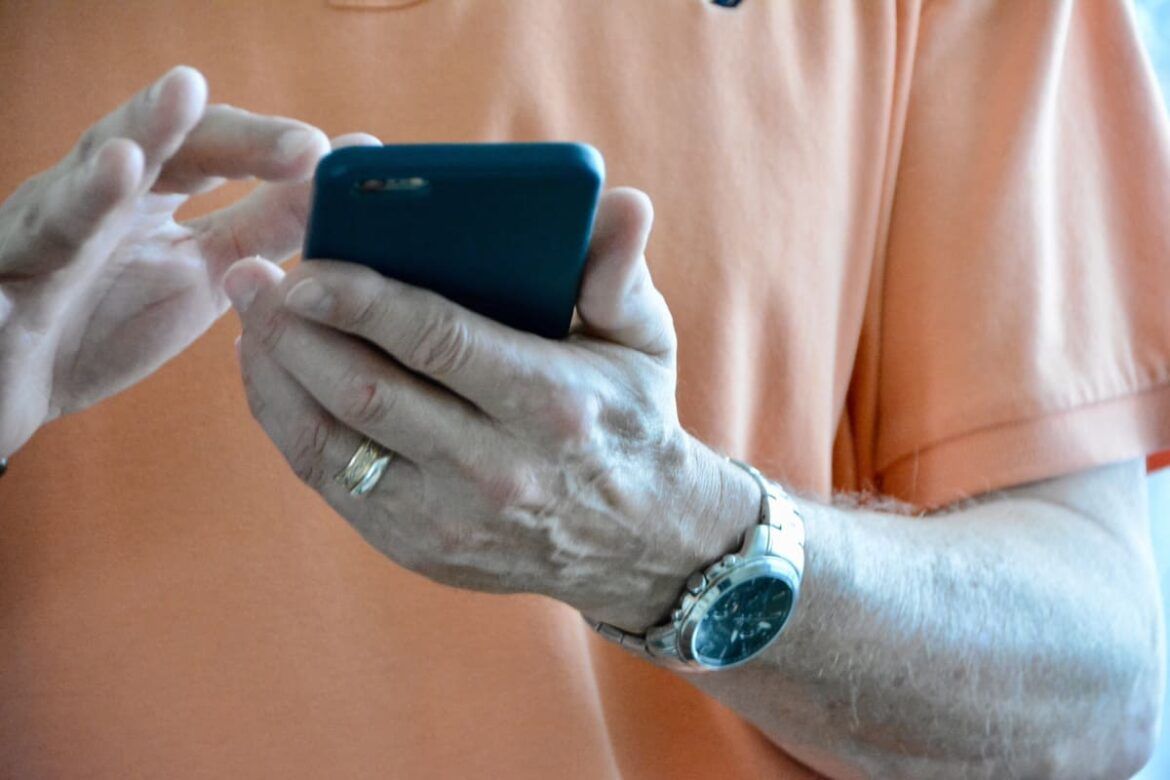 Homem segurando um celular em suas mãos, para ilustrar um texto que fala sobre o celular seguro aplicativo governo