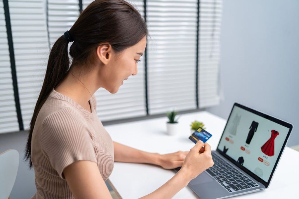 Mulher segurando cartão de crédito e acessando e-commerce da Shopify. 