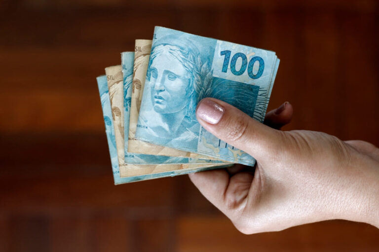 Pessoa segurando dinheiro esquecido no Valores a Receber.