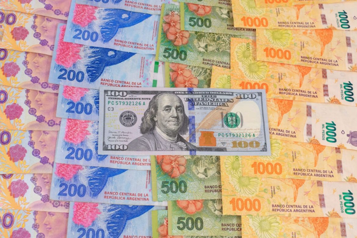 Nota de dólar em cima de notas argentinas para falar sobre dólar Coldplay na Argentina.
