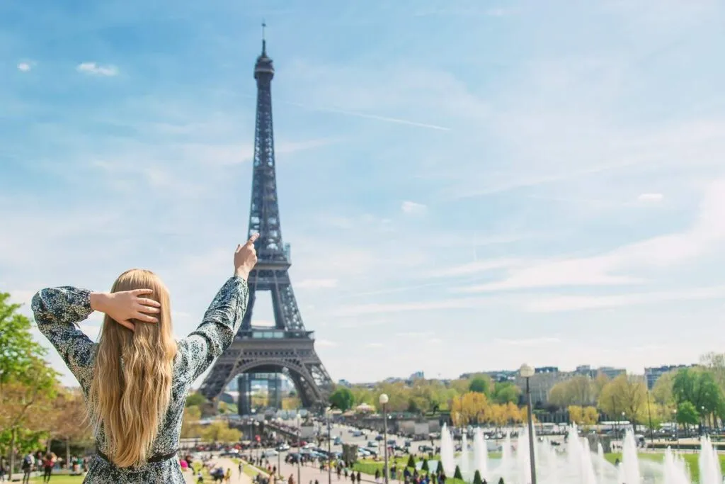 Mulher apontando para a Torre Eiffel em Paris.