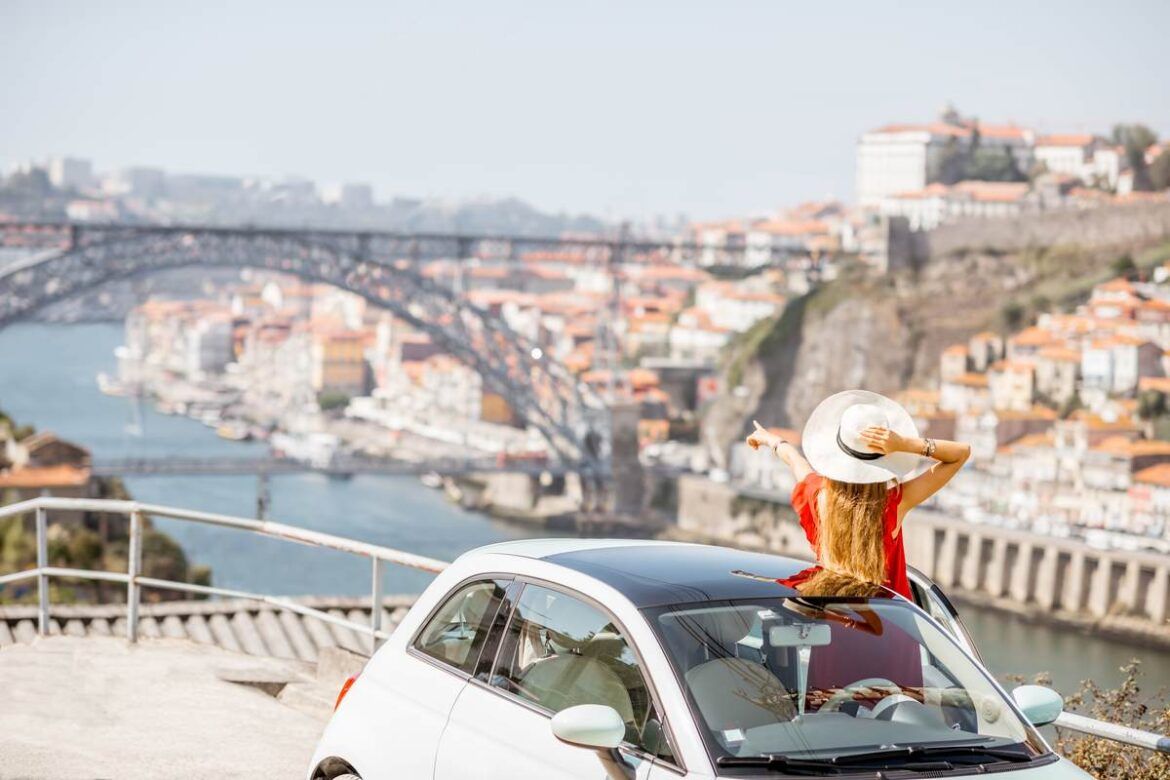 Mulher admirando a vista da cidade do Porto no seu carro alugado.