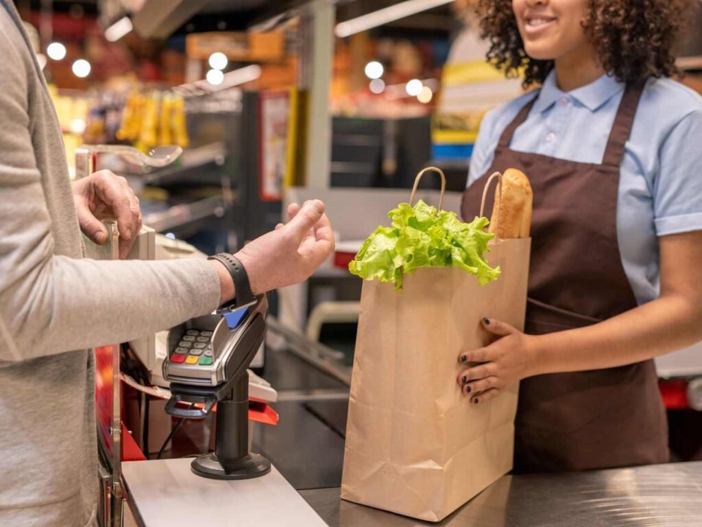 Homem pagando compras do supermercado com salário mínimo na Irlanda.