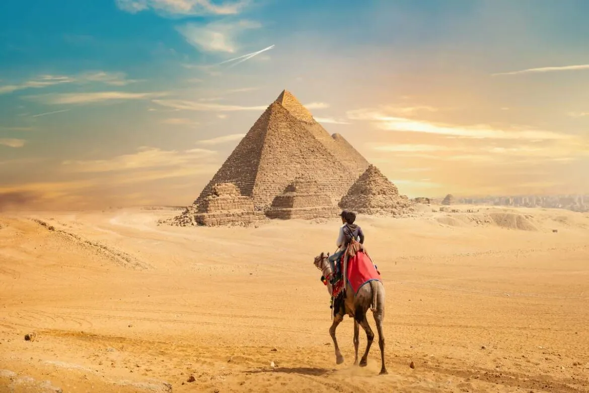 Homem no camelo andando em direção as pirâmides do Egito.
