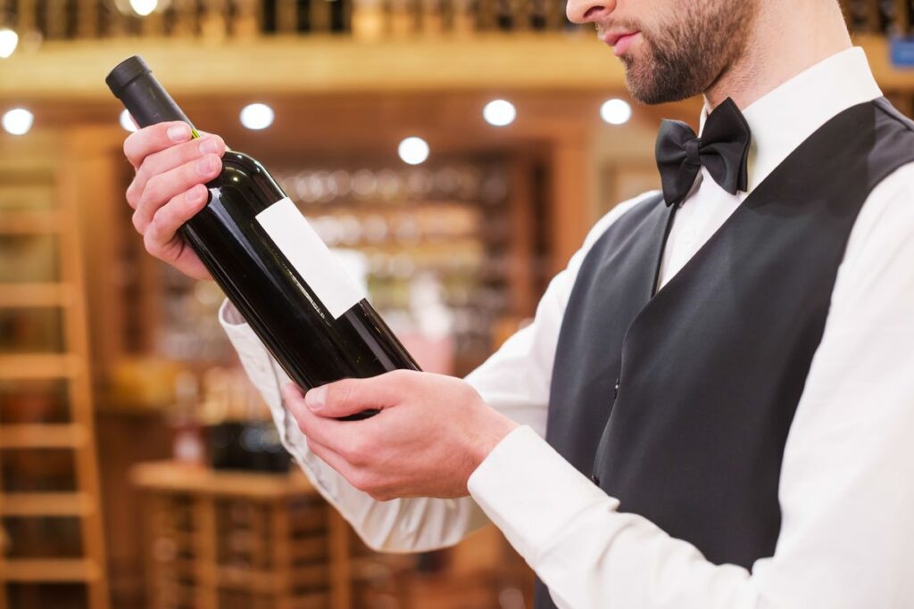 Garçom avaliando o rótulo do vinho no restaurante com estrela Michelin.