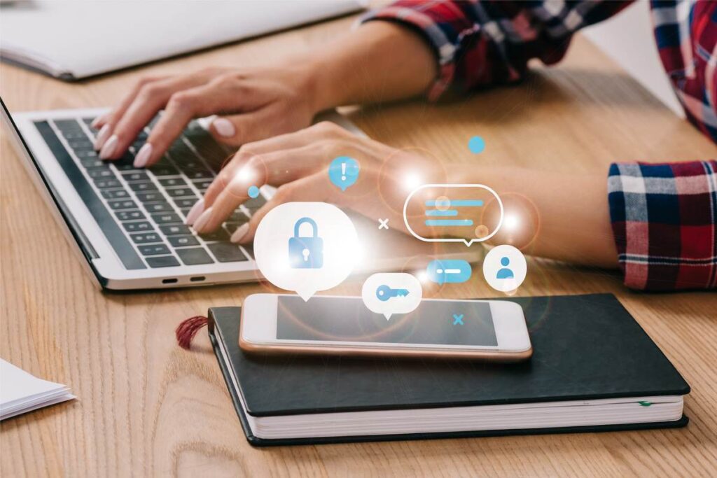 Homem usando o notebook com VPN com smartphone ao lado.