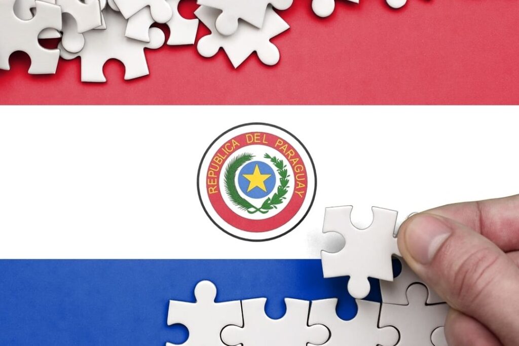 Pessoa montando um quebra-cabeça e cima da bandeira do Paraguai.