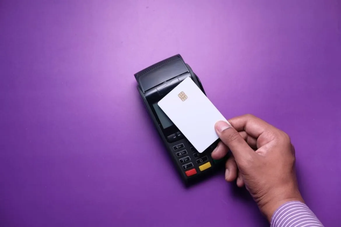 Pessoa usando um cartão de crédito simulando ser Nubank Ultravioleta.
