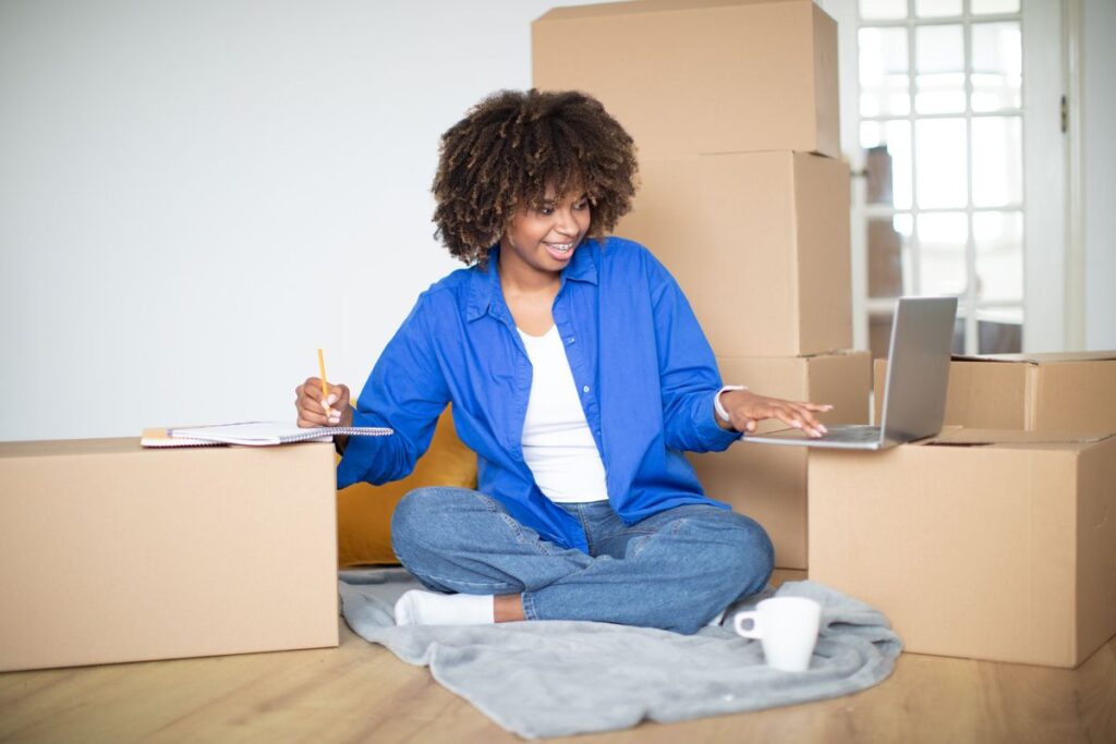 Mulher pesquisando apartamentos para comprar em Lisboa online com caixas ao fundo.