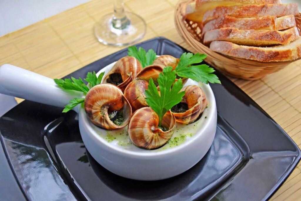 Prato de escargot com fatias de pão ao lado.